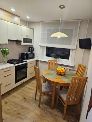 a kitchen with a table and chairs with a bowl of fruit on it at E D Arena View Apartment in Šiauliai