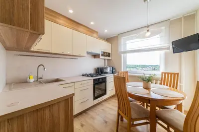 a kitchen with a wooden table and a dining room at E D Arena View Apartment in Šiauliai