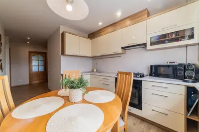 a kitchen with a wooden table with chairs and a dining room at E D Arena View Apartment in Šiauliai