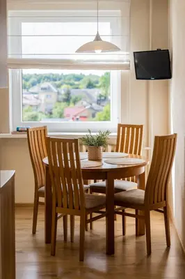 a dining room table with four chairs and a window at E D Arena View Apartment in Šiauliai