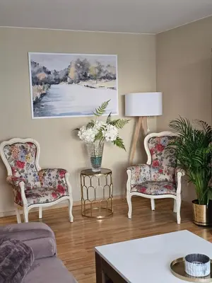 a living room with two chairs and a vase of flowers at E D Arena View Apartment in Šiauliai