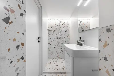 a white bathroom with a shower and a sink at Vega Self Checkin in Vilnius
