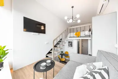 a living room with a couch and a staircase at Vega Self Checkin in Vilnius