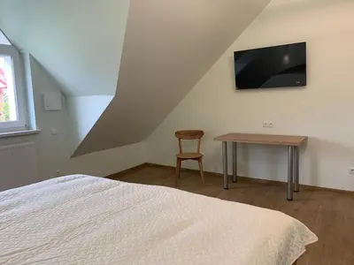 a bedroom with a bed and a table and a television at Green House in Ramučiai