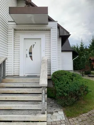 a white house with a white door and stairs at Green House in Ramučiai