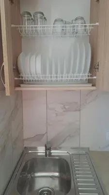 a kitchen with a sink and a shelf with dishes at Jaukaus buto nuoma Šiaulių rajone in Šapnagiai