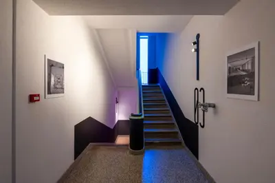 a hallway with a staircase with a blue stair light at Nemunas Park Apartment in Prienai