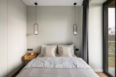 a bedroom with a bed with white walls and a window at Nemunas Park Apartment in Prienai
