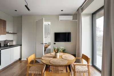 a kitchen and dining room with a table and chairs at Nemunas Park Apartment in Prienai