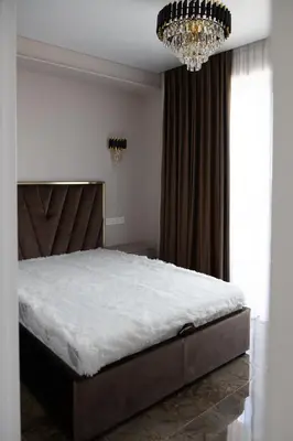 a bedroom with a large bed and a chandelier at VIXI Skylum in Vilnius