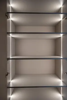 an empty closet with lights on the shelves at VIXI Skylum in Vilnius