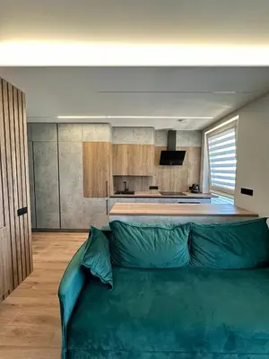 a living room with a green couch in front of a kitchen at Budiniškiu apartamentai in Vilnius
