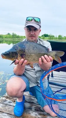 a man sitting on a dock holding a fish at Pineplace trio KOPA in Žaugėdai