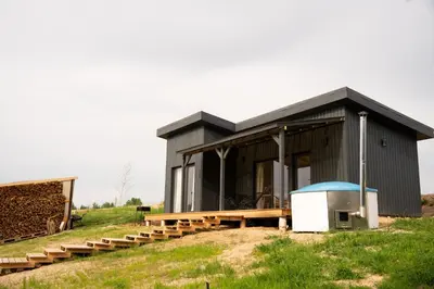 a black house on top of a grassy hill at Pineplace trio JŪRA in Žaugėdai