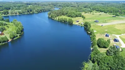 an aerial view of a river with trees and grass at Pineplace trio JŪRA in Žaugėdai