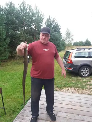 a man standing on a deck holding a stick at Pineplace trio JŪRA in Žaugėdai