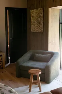 a living room with a couch and a stool at Kupetaite - Straw Bale Cabin in Nature in Družai
