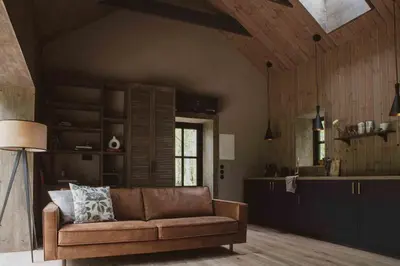 a living room with a couch and a kitchen at Kupetaite - Straw Bale Cabin in Nature in Družai
