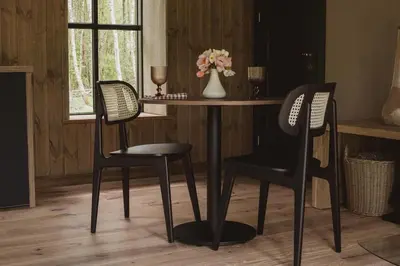 a table with two chairs and a vase with flowers at Kupetaite - Straw Bale Cabin in Nature in Družai