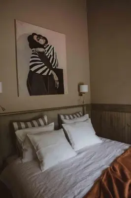 a bed in a bedroom with a picture of a woman at Kupetaite - Straw Bale Cabin in Nature in Družai