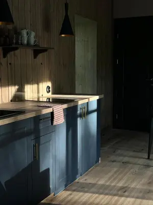 a kitchen with blue cabinets and a counter top at Kupetaite - Straw Bale Cabin in Nature in Družai