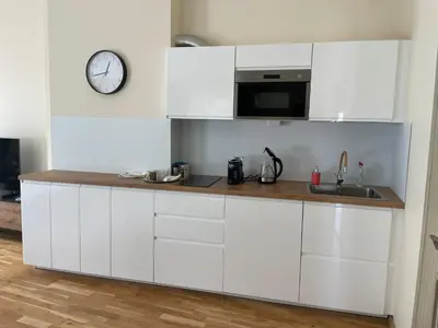 a kitchen with white cabinets and a clock on the wall at Vilijos apartamentai in Kaunas