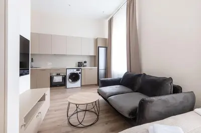 a living room with a black couch and a kitchen at StudioApart23 in Vilnius