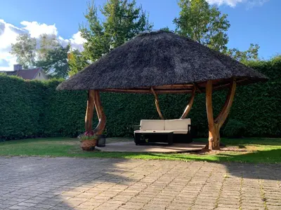 a pavilion with a couch under a straw roof at Kepezinski SPA apartments in Kaunas