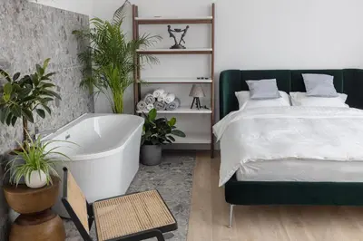 a bedroom with a bed and a bath tub and plants at PLENTO g APARTAMENTAI BIRŽUOSE in Biržai