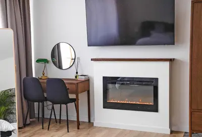 a living room with a fireplace with a tv above it at PLENTO g APARTAMENTAI BIRŽUOSE in Biržai