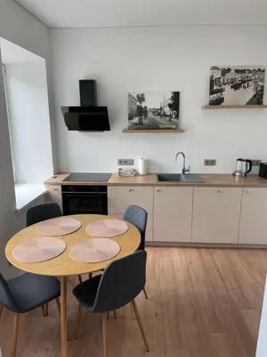 a kitchen with a wooden table and chairs in a kitchen at Vilkmerge apartment in Ukmergė