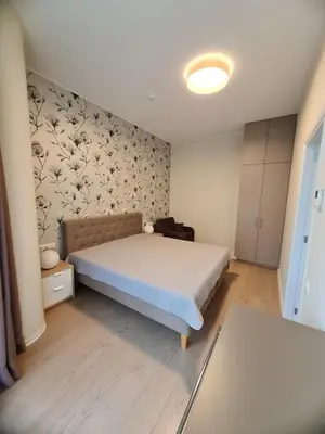 a bedroom with a bed and a wall with flowers at Saulės Muzika in Druskininkai