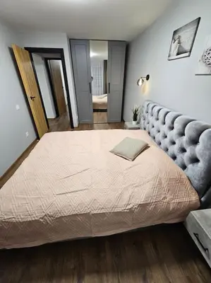 a bedroom with a large bed with a padded headboard at Trakai City apartment 2-bedroom in Šiauliai