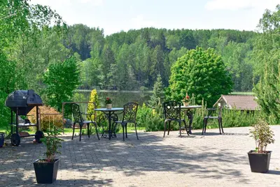 a patio with tables and chairs with a view of a lake at Green Harmony in Antalgė