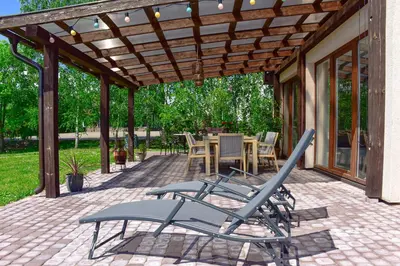 a patio with chairs under a wooden pergola at Green Harmony in Antalgė