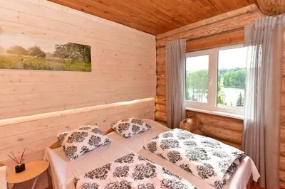 a bedroom with wooden walls and a bed with pillows at Green Harmony in Antalgė