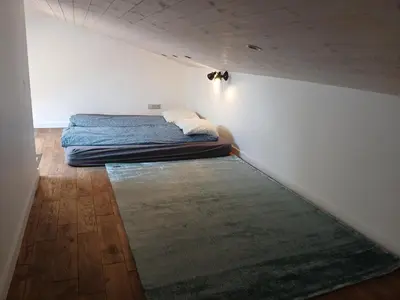 a small bedroom with a bed and a rug at Loft style studio in the Old Town in Kaunas
