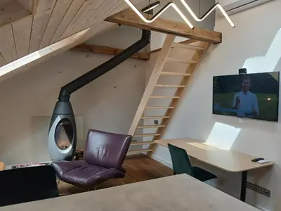 an attic room with a wood stove and a desk at Loft style studio in the Old Town in Kaunas