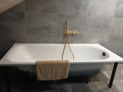 a white bath tub with a gold faucet in a bathroom at Loft style studio in the Old Town in Kaunas