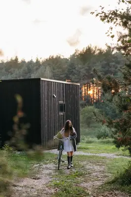 a woman walking a bike down a dirt road at Konga Stay M - Private Jacuzzi Included in Strakiškiai