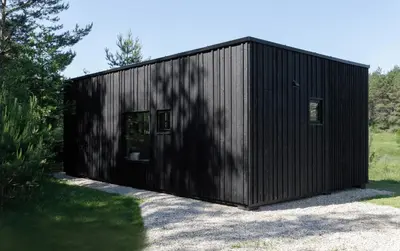a black building with two windows and a door at Konga Stay M - Private Jacuzzi Included in Strakiškiai