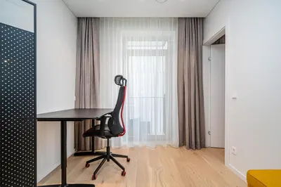 a desk and a chair in a room with a window at Scandinavian style apartment in Vilnius