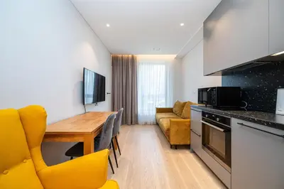 a kitchen and living room with a table and yellow chairs at Scandinavian style apartment in Vilnius