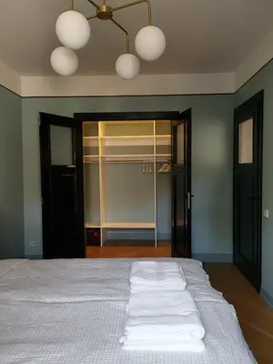 a bedroom with a bed with white sheets and a closet at Saviciaus in Vilnius