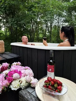 a man and a woman in a bath tub with a bottle of wine at Svečių namelis KNYGŲ NAMAS in Kelmė