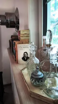 a shelf with glass bottles on a table with books at Svečių namelis KNYGŲ NAMAS in Kelmė