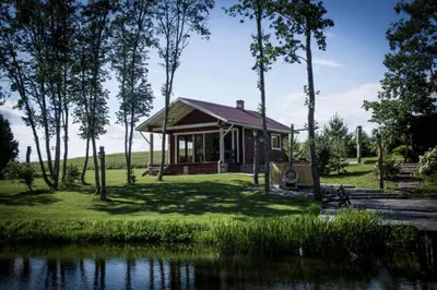 a small house next to a body of water at kaimo turizmo sodyba Fliorencija in Pasandravys