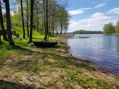 a body of water with a boat on the shore at Pirtis su ežero pakrante Trakai in Salkininkai