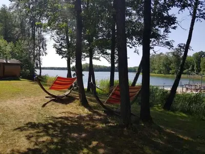 two hammocks are tied to trees near a lake at Pirtis su ežero pakrante Trakai in Salkininkai