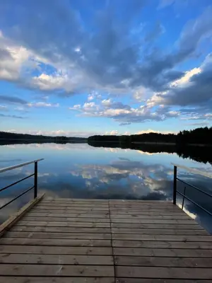 a dock on a lake with a cloudy sky at Poilsiadienis in Aukštadvaris